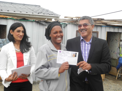 Cllr Derrick America (right) hands over ID card to community leader Verona Joseph (centre) with Salisha Lauton (left, Habitat for Humanity SA)
